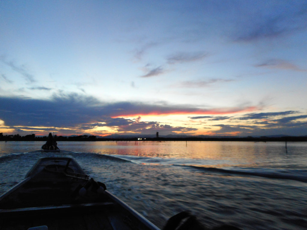 漁に出る船と夕焼けに染まる湖