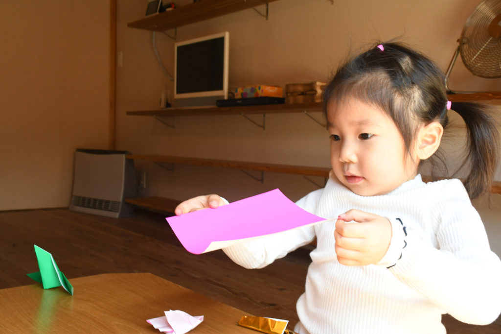折り紙で遊ぶ子